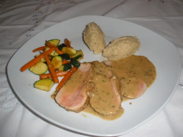 Rosa gebratenes Schweinsfilet in Käsesoße mit Couscous und Gemüse